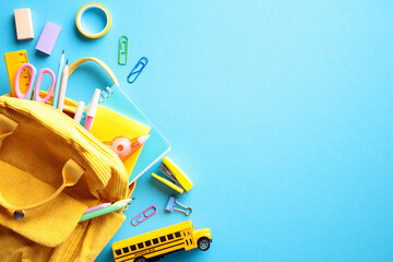 Vibrant School Supplies Flat Lay: A cheerful composition featuring a yellow backpack overflowing...