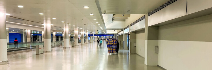 Modern airport interior with a worker pushing a blue cart, signifying travel, business commute, and...