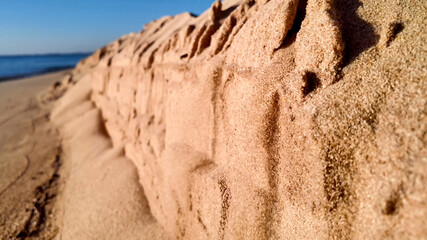 Close-up of a textured sand formation on a beach, with blurred ocean background, ideal for summer...