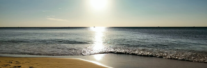 Serene beach landscape at sunset with gentle waves and sparkling reflection, ideal for travel...
