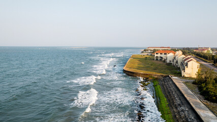 Coastline with gentle waves, seaside promenade, and old buildings, evoking summer travels and beach...