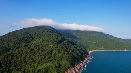 Aerial view of a tranquil misty mountain beside a serene coastline, ideal for themes of eco-tourism, Earth Day, and nature conservation