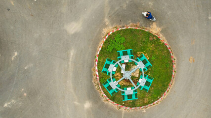 Aerial view of a solitary person sitting near a circular bench arrangement in a park, conveying...