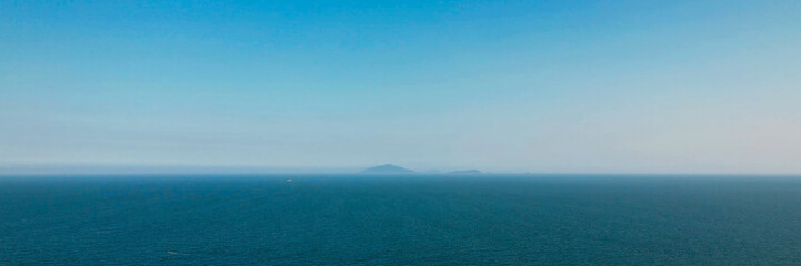 Serene ocean panorama with distant islands under a clear blue sky, ideal for themes of tranquility,...