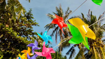 Colorful pinwheels spinning in a tropical setting with palm trees, representing childhood, summer...