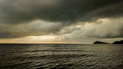 Dramatic seascape with impending storm clouds over tranquil water, ideal for conveying mood in...