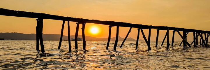 Serenity at sunset with a wooden pier silhouette over calm waters, ideal for travel themes, summer...