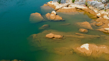 Tranquil freshwater lake with submerged and exposed brown rocks, suitable for themes like nature conservation, Earth Day, and serene landscapes