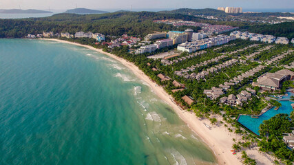 Aerial view of a tropical beachfront resort with lush greenery, ideal for travel and summer...