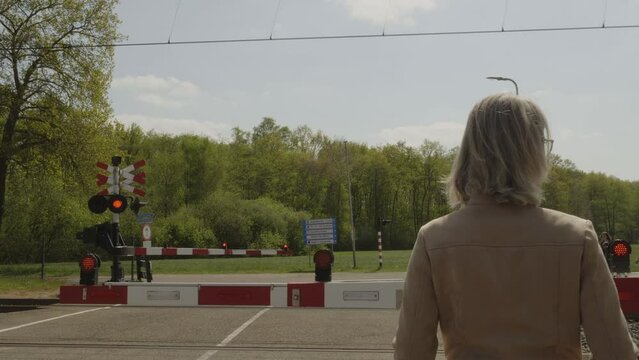 Woman waiting for Arriva train to pass level crossing near Dalfsen station