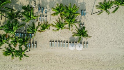 Aerial view of a serene tropical beach with sun loungers and palm trees, ideal for travel and...