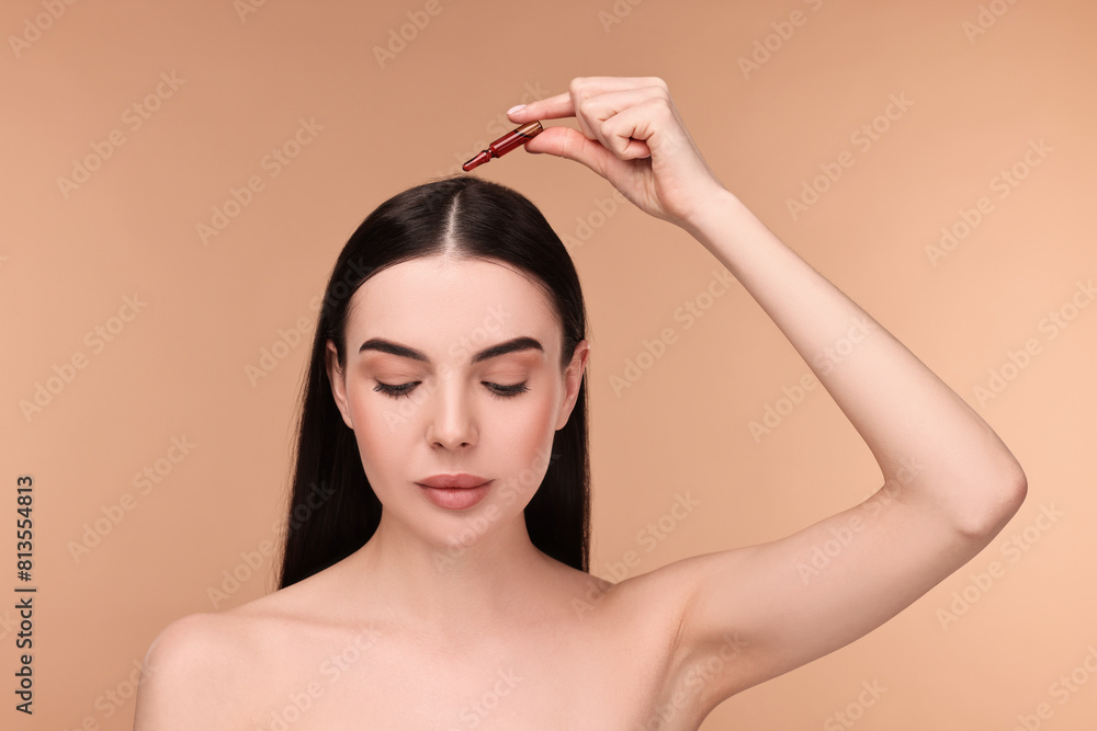 Sticker Beautiful young woman using ampoule for hair treatment on beige background