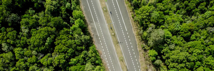 Aerial view of a deserted road cutting through a dense forest, symbolizing concepts of travel,...