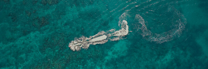 Aerial view of a speedboat cutting through turquoise waters, creating foamy wake, perfect for...