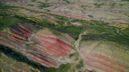 Aerial view of colorful, stratified rock formations in a desert landscape, ideal for geology and...