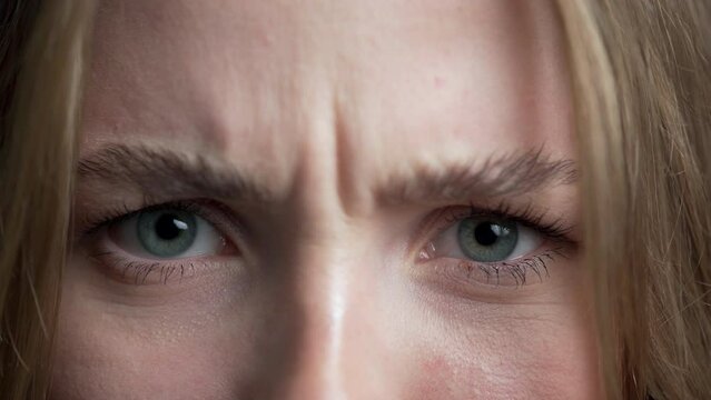 Close-up of female face frowning. Girl with blue eyes looking at camera. Concept of anger and skepticism.