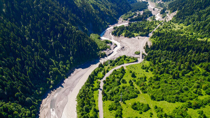 Aerial view of a winding river cutting through a lush green mountain forest, showcasing nature,...