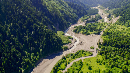 Aerial view of a winding river cutting through a lush green mountain forest, showcasing nature,...