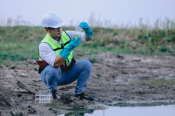 Asian man environment researcher holds tube of sample water to inspect from the lake. Concept, explore, analysis water quality from natural source. Ecology field research