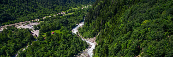Aerial view of a winding river cutting through a lush green mountain forest, showcasing nature, environment, and Earth Day concept