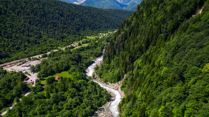 Aerial view of a winding river cutting through a lush green mountain forest, showcasing nature, environment, and Earth Day concept