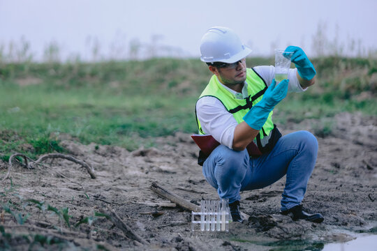 Asian man environment researcher holds tube of sample water to inspect from the lake. Concept, explore, analysis water quality from natural source. Ecology field research