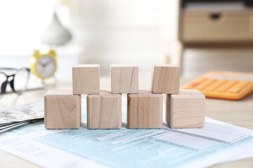 Taxes. Wooden cubes and documents on table, closeup