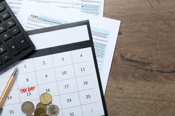 Calendar with date reminder about tax day, coins, documents and calculator on wooden table, top...