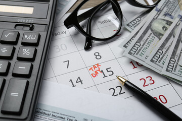 Fototapeta premium Calendar with date reminder about tax day, documents, money, pen, calculator and glasses on table, closeup