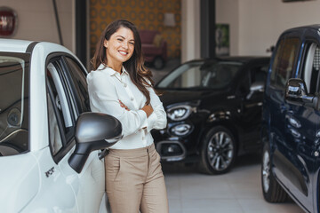 Smiling saleswoman looking at camera at new car showroom. Professional car dealer posing proudly at...