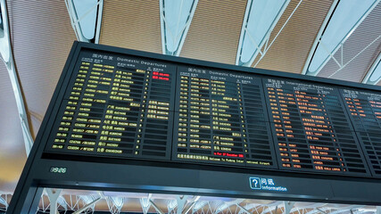 Close-up of an airport departure board showing flight information, reflecting travel and holidays...