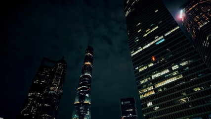 Dramatic night skyline with illuminated skyscrapers against a dark sky, conveying concepts of...