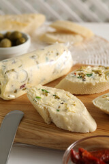 Tasty butter with olives, green onion and bread on table, closeup