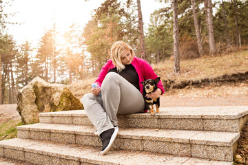Overweight woman running with dog in nature, resting after workout. Exercising outdoors for people with obesity.