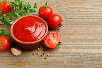 Tasty ketchup, fresh tomatoes, parsley and spices on wooden table. Space for text