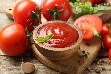 Tasty ketchup, fresh tomatoes, basil and spices on wooden table