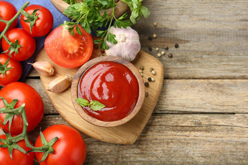 Tasty ketchup, fresh tomatoes, parsley and spices on wooden table, flat lay. Space for text