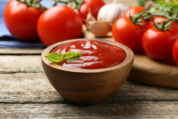 Tasty ketchup, fresh tomatoes, basil and spices on wooden table