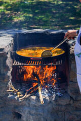 close-up of the hand of a cook cooking a typical Spanish paella over a fire in the countryside