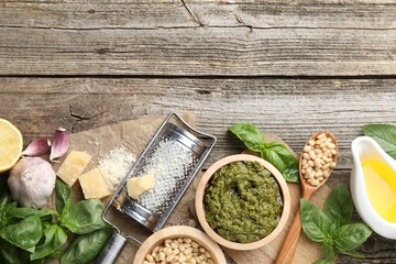 Tasty pesto sauce, basil, pine nuts, cheese, garlic and oil on wooden table, top view. Space for text
