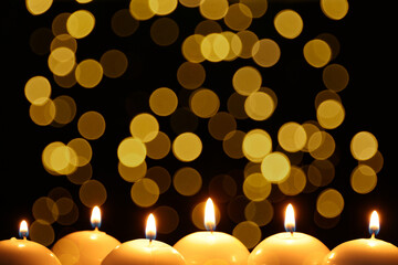 Many burning candles in darkness, bokeh effect