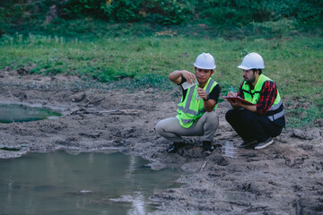 Portrait of asian male scientist and asian male biologist comparing test tubes with samples of polluted water, taken from mountain river and discussing results of analysis during research