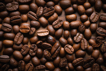 Naklejka premium Close up coffee grain on natural wood background showcasing the rich, dark grain patterns, perfect for a rustic or organic setting, Food Concept