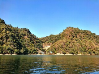 Beautiful view of a lake reflecting the blue sky with a tree-covered mountain in the background