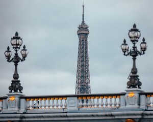 Top of the famous Eiffel tower in the background of the Pont Alexandre III