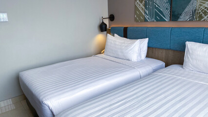 hotel bed with white sheets and a blue pillow on it