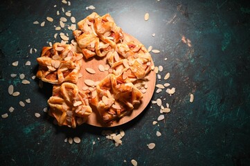 Top view of apple turnover pies decorated with almonds on a wooden board