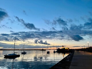 Boats on the surface of sea in the evening with the Dun Laoghaire lighthouse on the background