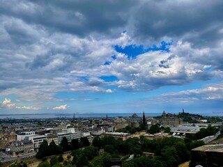 Drone shot of buildings, houses and lush trees in Edinburgh, Scotland, under the cloudy sky