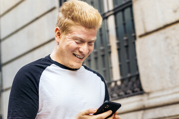 Young albino man using smartphone in the city